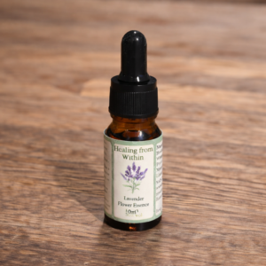Amber glass dropper bottle of Lavender flower essence with printed lavender illustration label, standing on a wooden surface in soft natural light.